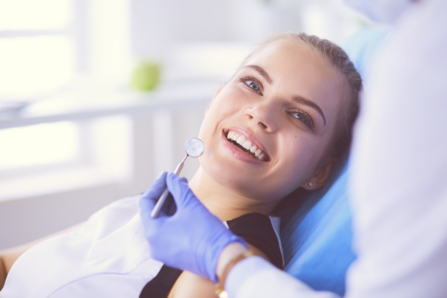 AdobeStock_226130914-Young-Female-patient-with-pretty-smile-examining-dental-inspection-at-dentist-office